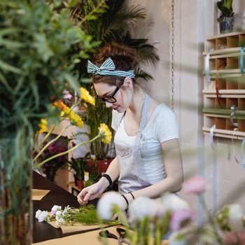 Woman florist making bouquet and working in flower shop